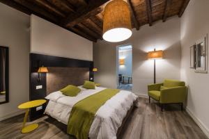 sypialnia z dużym łóżkiem i zielonym krzesłem w obiekcie Dolcevita Apartments w Rzymie
