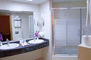 a bathroom with a tub, sink and mirror at Geneva Hotel in Amman