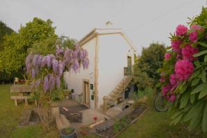 uma pequena casa com flores roxas no quintal em Moinho do Prado em Vila Nova de Cerveira