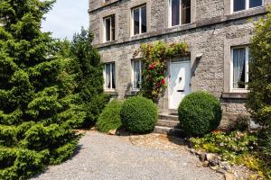 a stone house with a white door and some bushes at Relax @ Maison Sax in Oppagne