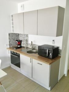 uma cozinha com armários brancos, um lavatório e um micro-ondas em CALVI em Calvi