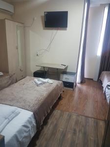 a room with two beds and a desk with a television at Hotel LEADER in Tbilisi City