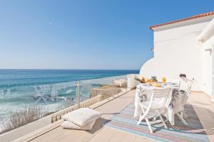 een balkon met een tafel en stoelen en de oceaan bij Cubo in Sintra