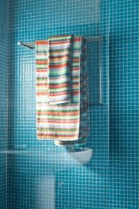 een blauw betegelde badkamer met een handdoek op een rek bij Cubo in Sintra +34 foto's