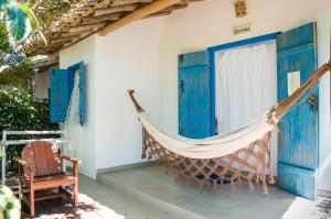 a hammock on the porch of a house with blue doors at Pousada San Antonio Praia in Caraíva