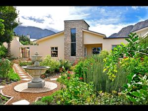 a garden with a fountain in front of a house at Petit & Grande Plaisir luxury self-catering in Franschhoek