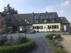 a large yellow house with a driveway in front of it at Grimmershof in Hürtgenwald