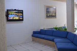 una sala de espera con sofá azul y TV en Touring Hotel, en Maringá