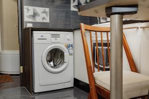 a washing machine in a room with a chair at Transitional Havryky Apartment in Lviv