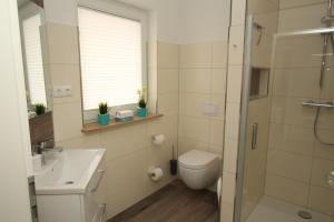 a bathroom with a toilet and a sink and a shower at Familienfreundliches Ferienhaus in Kröpelin in Kröpelin +10 photos