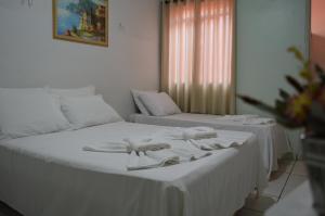 1 dormitorio con 2 camas con sábanas blancas y ventana en Touring Hotel, en Maringá