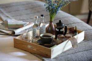 a wooden tray with a cup of coffee and bottles on a bed at Horse and Groom in Moreton in Marsh