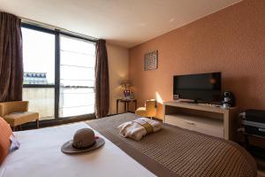 a hotel room with a bed and a flat screen tv at Mercure Vichy Thermalia in Vichy