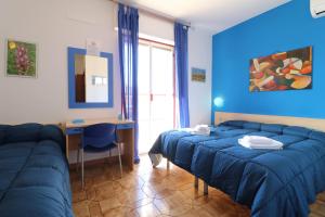 a bedroom with blue walls and a bed and a desk at B&B Spiaggia di Ponente in Scicli