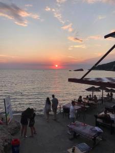 - un groupe de personnes debout sur la plage pour admirer le coucher du soleil dans l'établissement Sunset Old Town, à Ulcinj