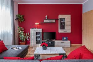 sala de estar con paredes rojas, sofá y TV en Apartment Bordeaux 29, en Rovinj