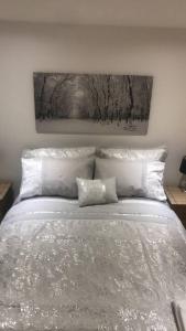 a bed with white pillows and a painting on the wall at The Chalet, 444 North Lochboisdale in Lochboisdale