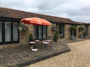 a patio with two chairs and an umbrella at Bagstone Court Barn in Rangeworthy