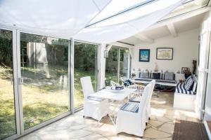 a conservatory with a table and chairs and glass doors at La Cormorandiere Plage in La Couarde-sur-Mer