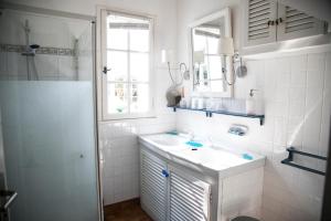 a white bathroom with a sink and a window at La Cormorandiere Plage in La Couarde-sur-Mer