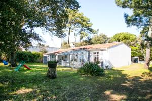 a white house in a yard with a tree at La Cormorandiere Plage in La Couarde-sur-Mer