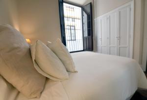 a bedroom with a white bed with pillows and a window at Apartamento Arenal in Seville