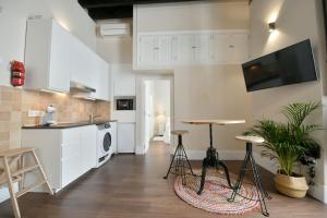 a kitchen with white cabinets and a table and stools at Apartamento Arenal in Seville