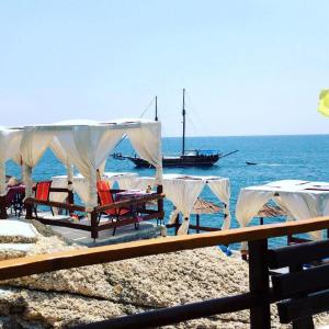 - un groupe de tables et de chaises sur une plage avec un bateau dans l'établissement Sunset Old Town, à Ulcinj