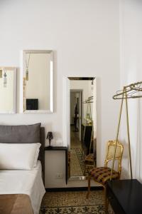 una camera da letto con specchio, letto e sedia di Ellie Luxury Apartment a Roma