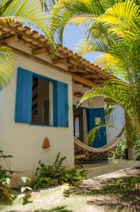 a house with blue windows and a palm tree at Pousada Bruma in Caraíva