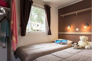 Un dormitorio con 2 camas con un osito de peluche y un libro en Camping Paris-Est, en Champigny-sur-Marne