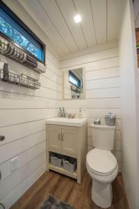 a bathroom with a toilet and a sink and a window at Stillwater House Elegant tiny container home Near Magnolia in Waco