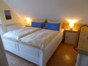 a bedroom with a large white bed with blue pillows at Ferienwohnungen im Osterkoog in Nordstrand
