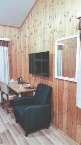 a living room with a table and a tv on a wooden wall at Guesthouse Skálafell in Skálafell