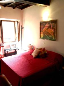 a bedroom with a red bed with a painting on the wall at Portico d'Ottavia, the ancient Rome in Rome