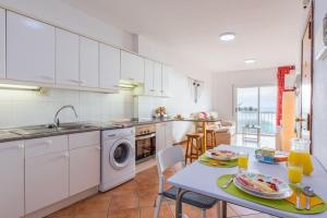 una cocina con armarios blancos y una mesa con una comida. en 1B WONDERFUL SEA VIEW Playa De Las Vistas, en Los Cristianos