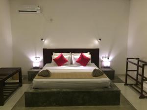 a bedroom with a large bed with two red pillows at Goddess Garden Sigiriya in Sigiriya