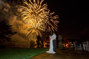 a bride and groom standing in front of fireworks at Melbourne Lodge in Welwyn