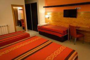 a hotel room with two beds and a desk and a television at Amérian Villa del Dique in Villa del Dique