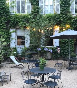 un patio al aire libre con mesas, sillas y una sombrilla en Les Chambres d'Hôtes du Bois Joli en Semur-en-Auxois