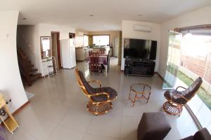 sala de estar de planta abierta con sillas y TV en Casa Flecha en Canoa Quebrada