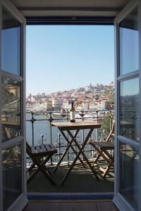 Porto View by Patio 25 في فيلا نوفا دي غايا: طاولة وكراسي على شرفة مطلة على الماء