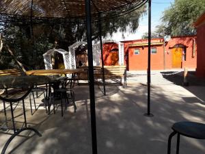 a patio with tables and chairs under an umbrella at Hostal Las Kañas in San Pedro de Atacama