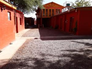 an empty alley with red buildings and gravel at Hostal Las Kañas in San Pedro de Atacama