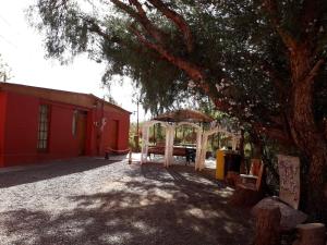 a red building with a gazebo and a tree at Hostal Las Kañas in San Pedro de Atacama