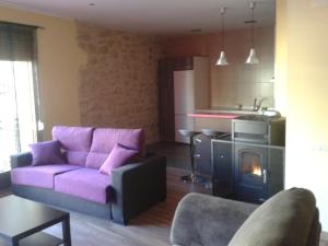 a living room with a purple couch and a kitchen at Apartamentos La Muralla in Horta de San Joan