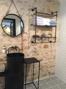 a bathroom with a round mirror and a black table at A l'orée de la forêt in Recloses