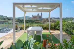 uma mesa branca num jardim com uma pérgola em Twilight Holiday Home em Għasri