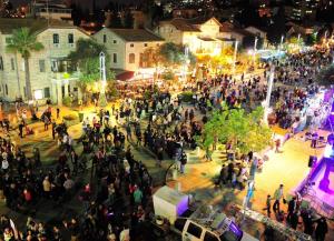 a crowd of people standing around a street at night at Pina Ba'Moshava in Haifa