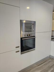 a kitchen with white cabinets and a microwave at Apartmentos Timas #1 in Praia